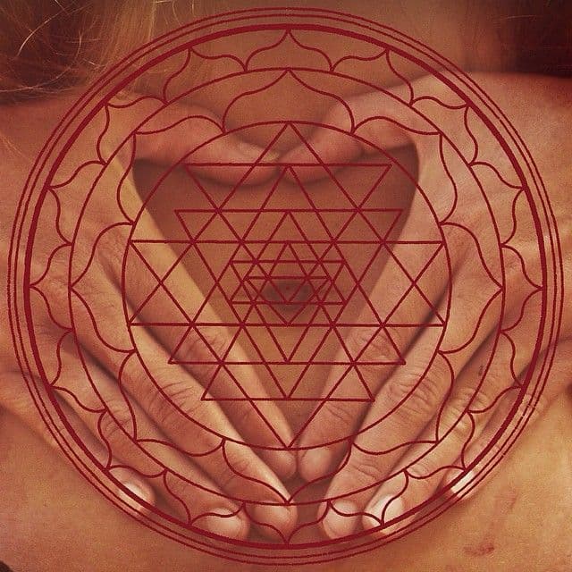 Hände formen ein Yoni-Mudra über dem Bauch, überlagert von einem roten Sri-Yantra-Mandala