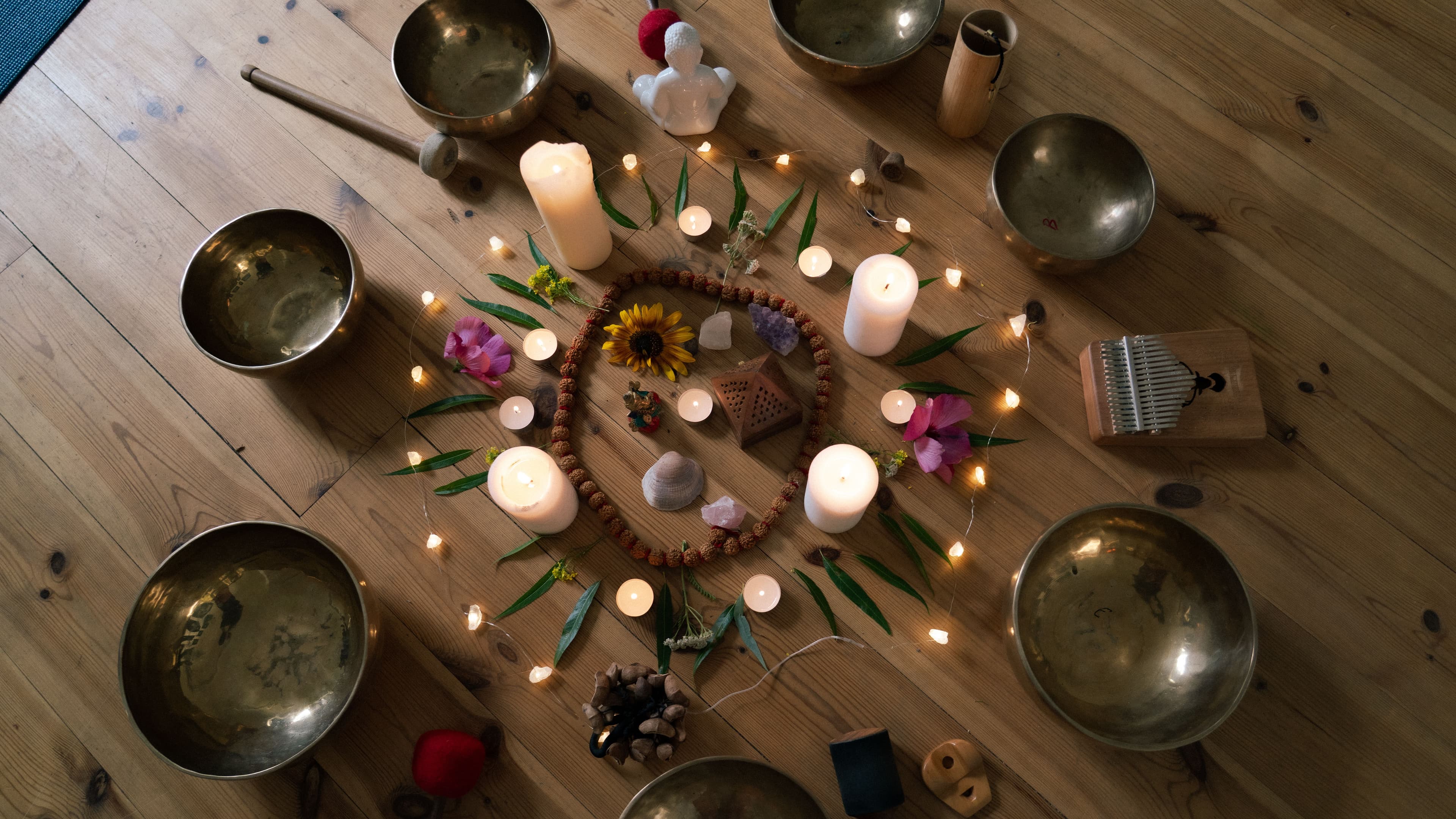 Zeremonie-Altar mit Klangschalen, Kerzen, Blumen und einer Kalimba im Kreis auf dem Studioboden