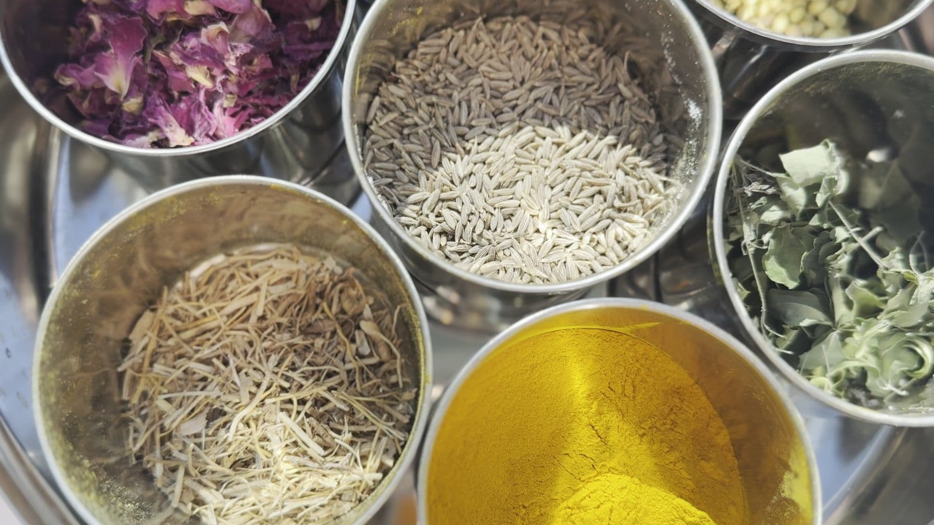 Ayurvedische Kräuter und Gewürze — Kurkuma, Kreuzkümmel, Rosenblüten und getrocknete Kräuter — bei einer Yogicescape Ayurveda-Ausbildung in Berlin